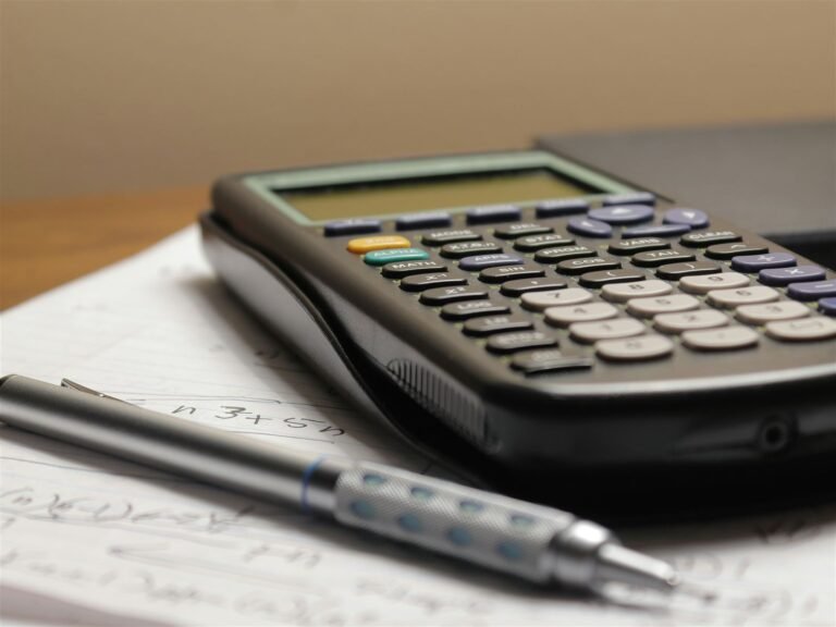 Graphing calculator and a mechanical pencil resting on a page of handwritten calculations
