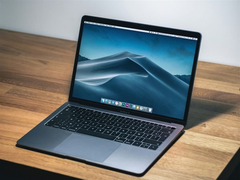 Open laptop displaying a desktop wallpaper, sitting on a wooden desk